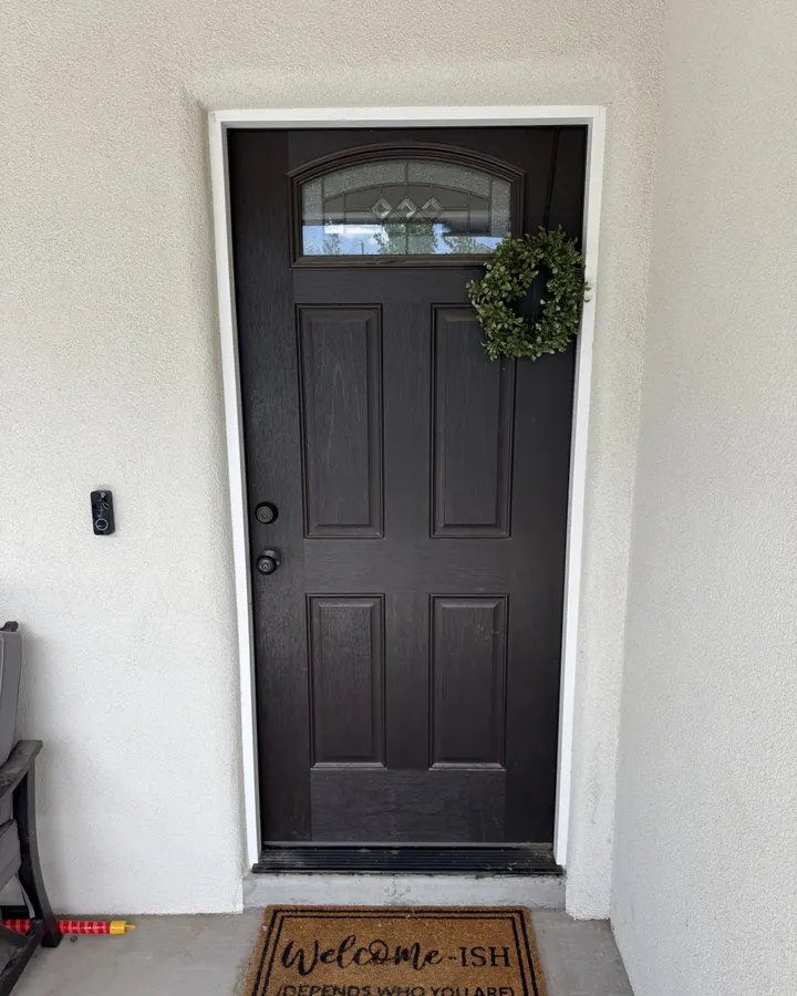 Black entry door in a finished stucco entry