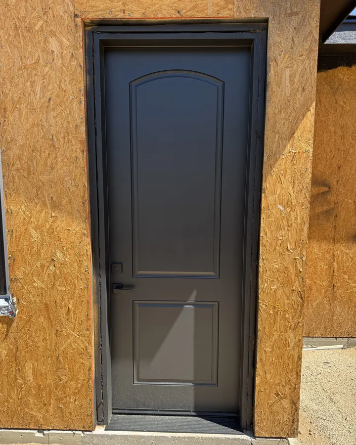 New dark exterior door hung in a sheathed opening