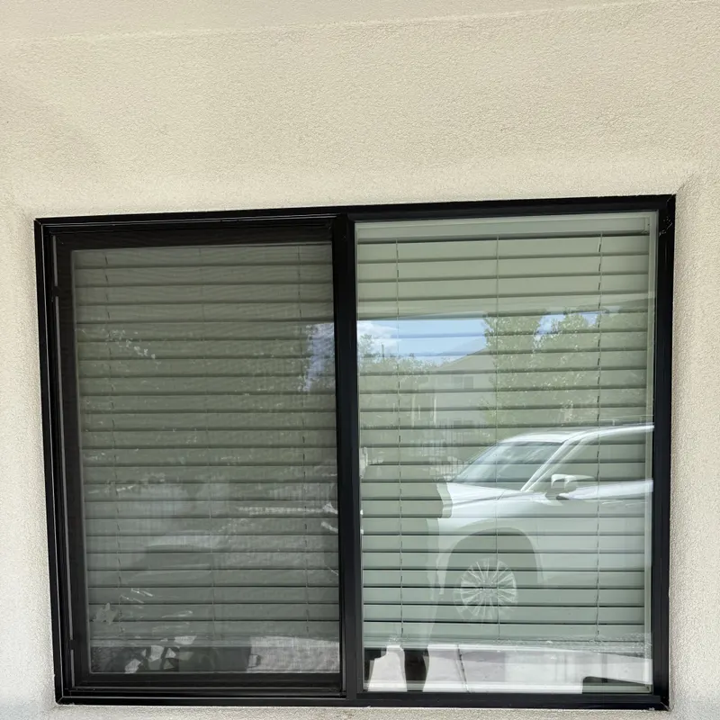 Black framed slider window in a finished stucco wall