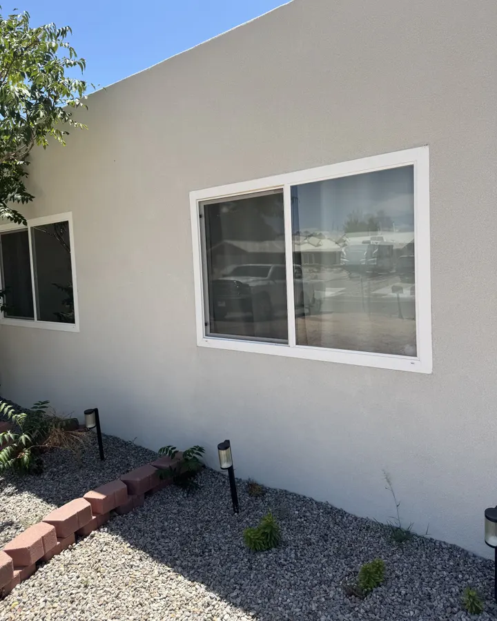 White window in a stucco wall above a gravel bed