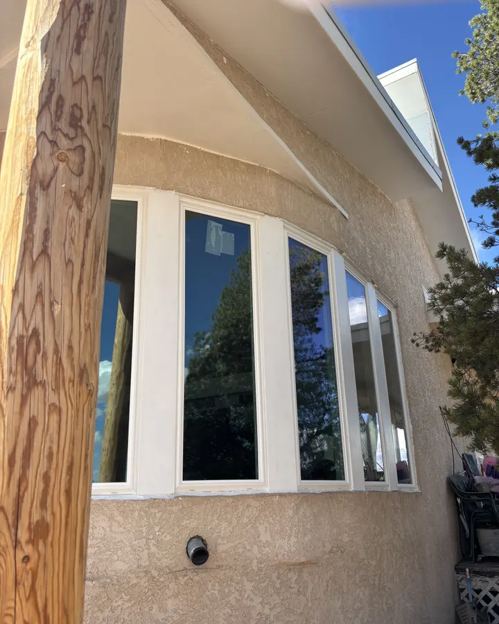 White windows in a stucco wall beside a wood post
