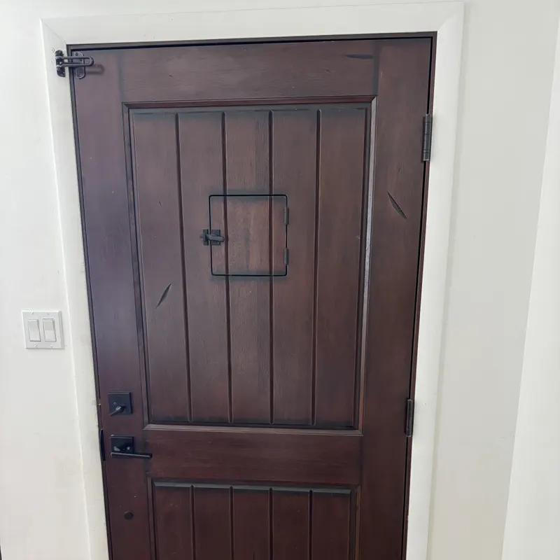 Interior side of a dark wood entry door with black hardware